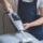 Man in uniform cleaning sofa with dry steam cleaner. Place for text.